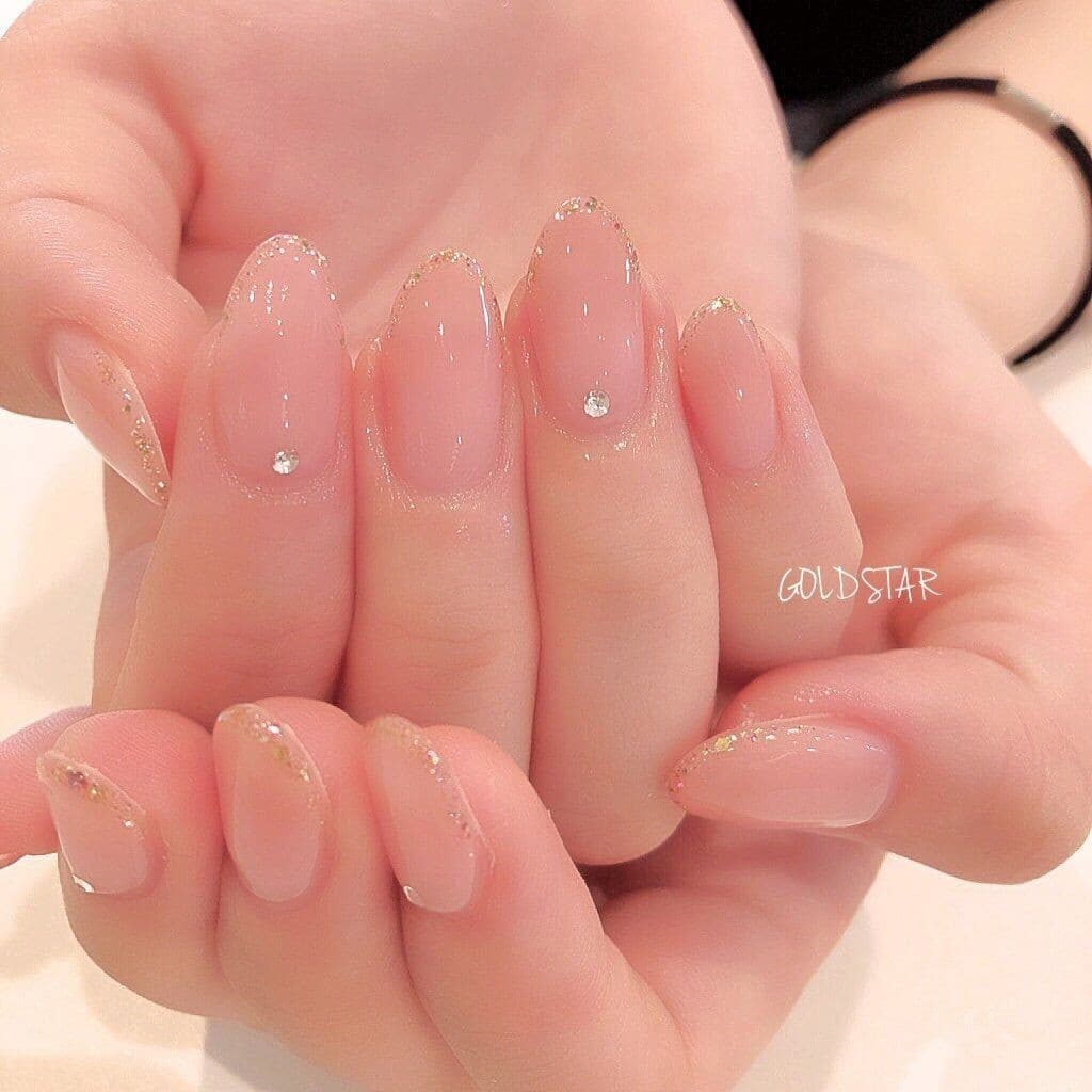 Manicura semipermanente nude con brillo dorado y acabado limpio